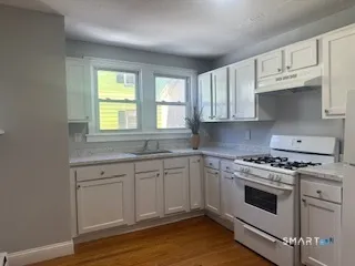 a kitchen with granite countertop white cabinets and white appliances