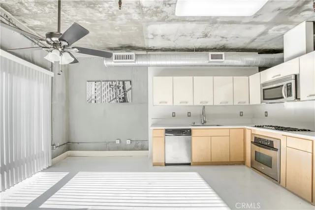 a large white kitchen with a large window a sink and stainless steel appliances