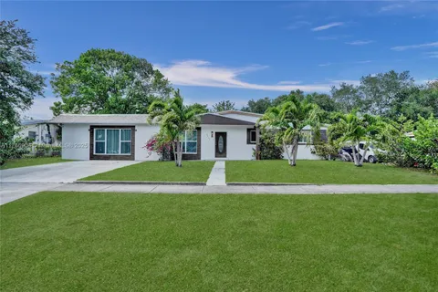 a view of house with a big yard and potted plants