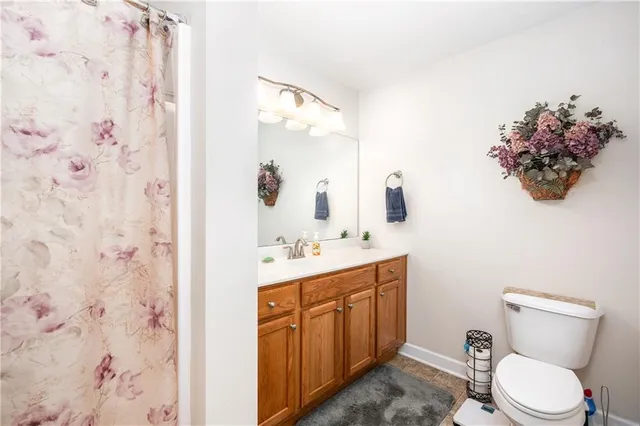 a bathroom with a toilet sink vanity granite and shower