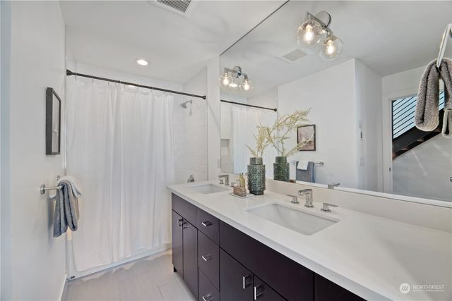 a bathroom with double vanity sink a mirror and shower