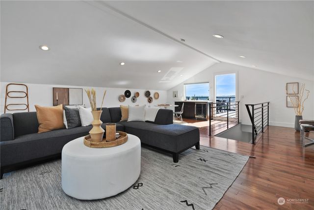 a living room with furniture kitchen view and a wooden floor