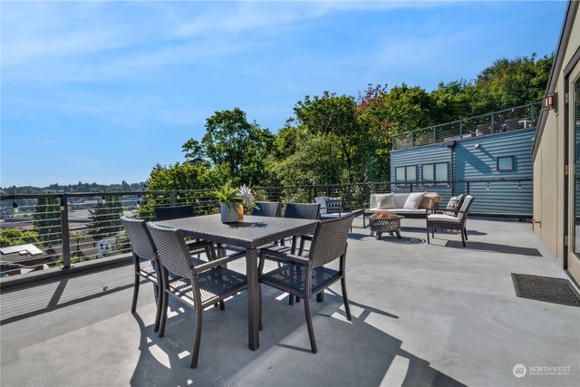 a view of a patio with table and chairs and potted plants with wooden floor and city view