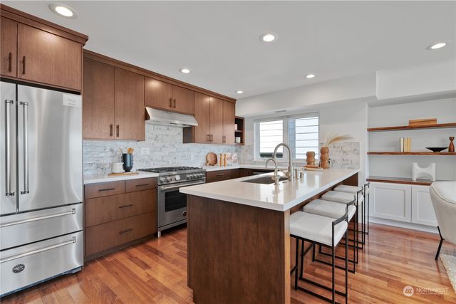 a large kitchen with cabinets wooden floor and stainless steel appliances