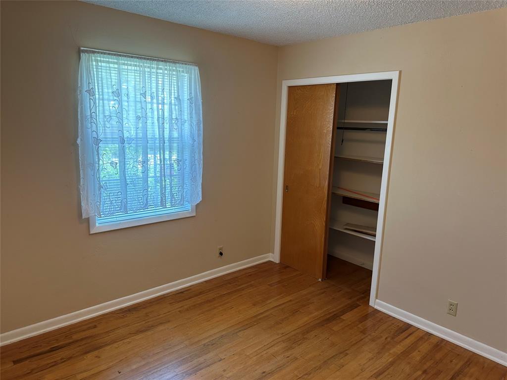 406 South Williams Street Hamilton, TX 76531 - Photo 16 of 35 an empty room with wooden floor closet and windows