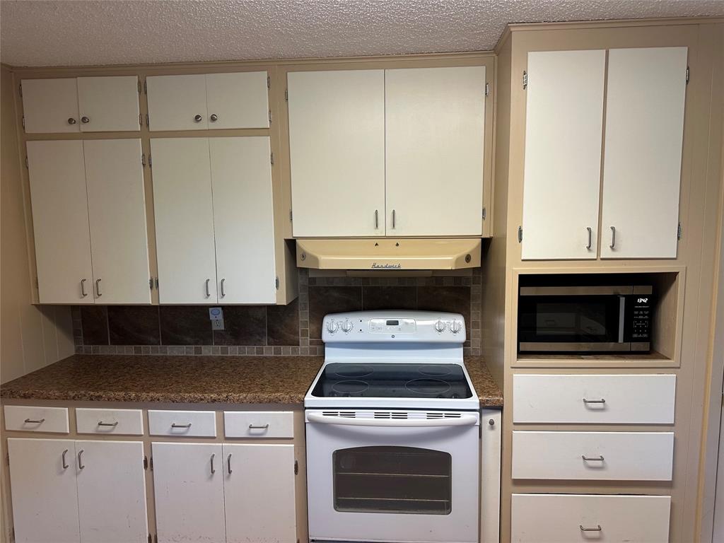 406 South Williams Street Hamilton, TX 76531 - Photo 10 of 35 a kitchen with a stove and white cabinets