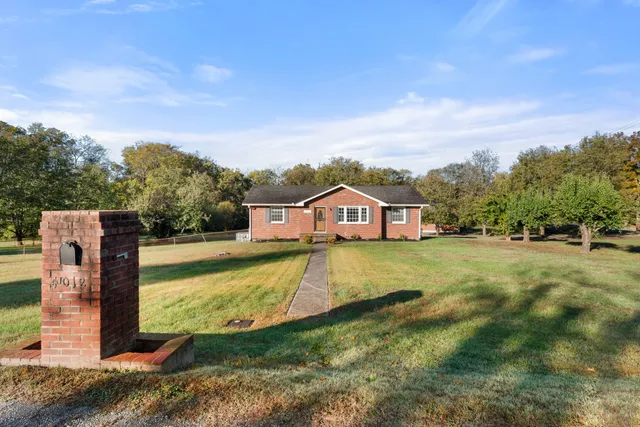 a view of a house with a big yard and large trees