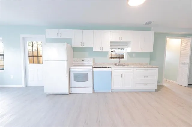 a kitchen with cabinets appliances a sink and a window