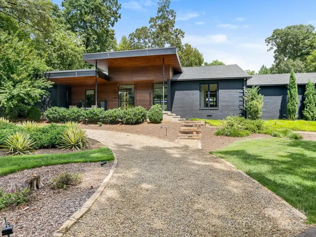 a front view of house with yard and trees in the background