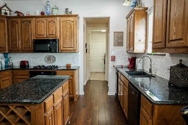 a kitchen with granite countertop a sink a stove and a wooden cabinets