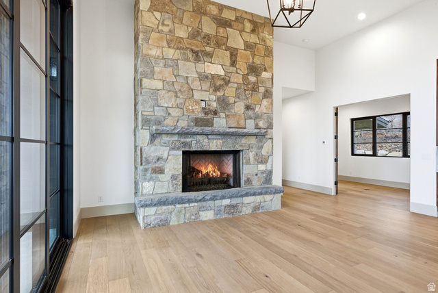 2155 East Wrangler Road Kamas, UT 84036 - Photo 41 of 62 Unfurnished living room with light wood-style flooring, a stone fireplace, and a high ceiling