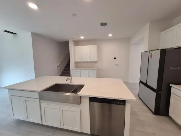 a kitchen that has a sink a refrigerator and a stove top oven