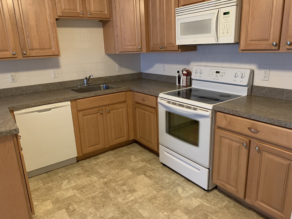 23 Elm Street, Unit 1 Manchester, MA 01944 - Photo 2 of 8 a kitchen with stainless steel appliances granite countertop a sink and a stove