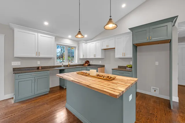 a kitchen with stainless steel appliances granite countertop a sink a stove and a wooden floors