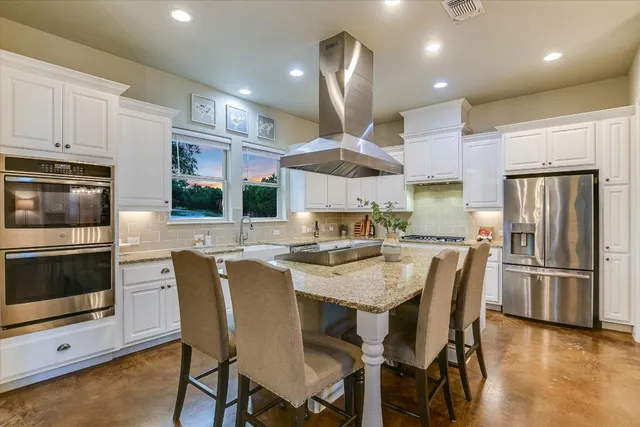a kitchen with stainless steel appliances a dining table chairs refrigerator and microwave