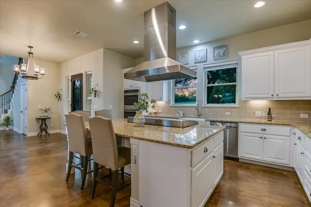 a kitchen with stainless steel appliances granite countertop wooden cabinets a stove a sink and a large window