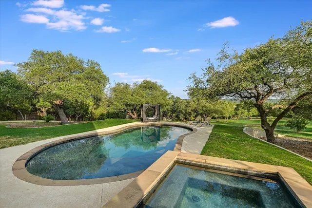 a view of a swimming pool with a yard and plants