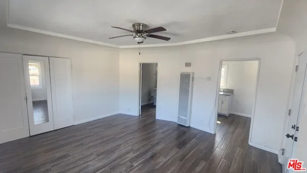a view of empty room with wooden floor and ceiling fan