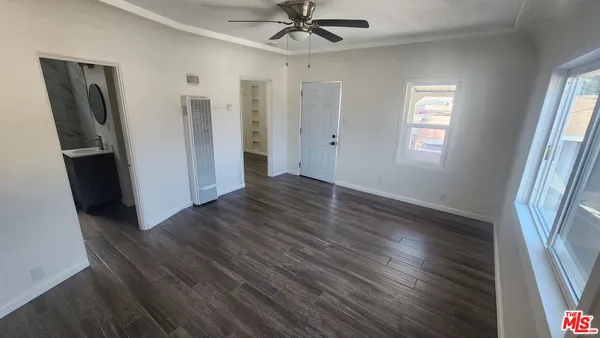 an empty room with wooden floor and a ceiling fan