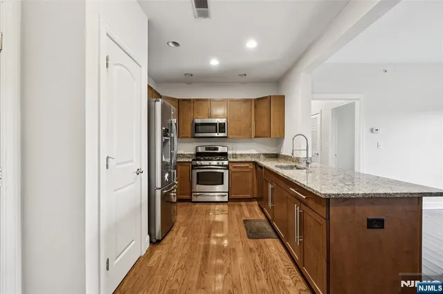 a kitchen with stainless steel appliances granite countertop a stove top oven a sink and a refrigerator