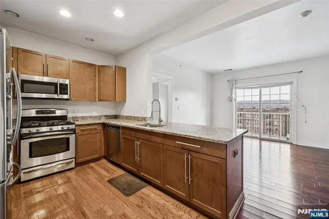 a kitchen with stainless steel appliances granite countertop a stove a sink and a microwave