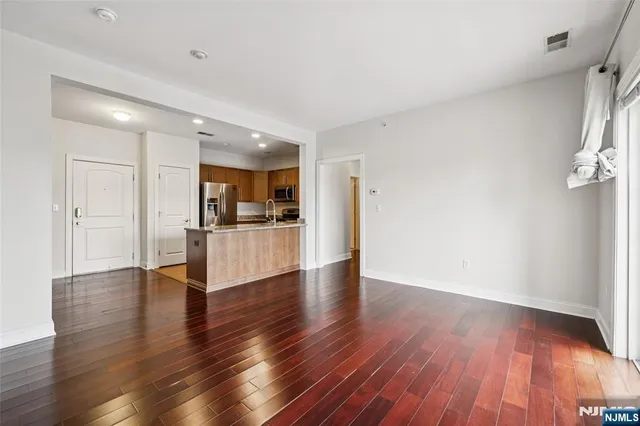 a view of a kitchen and an empty room with wooden floor