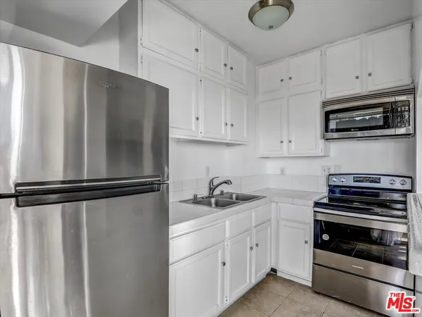 a kitchen with white cabinets and black appliances