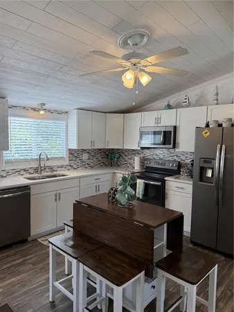 a kitchen with stainless steel appliances granite countertop a stove a refrigerator a sink dishwasher a dining table and chairs with wooden floor
