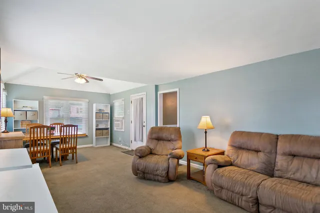 a living room with furniture and a dining table with bookshelf