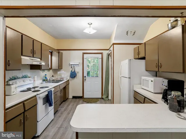 a kitchen with stainless steel appliances granite countertop a stove a refrigerator a sink and white cabinets