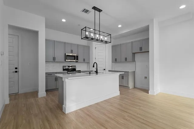 a kitchen with stainless steel appliances granite countertop a refrigerator a stove top oven a sink dishwasher and white cabinets with wooden floor