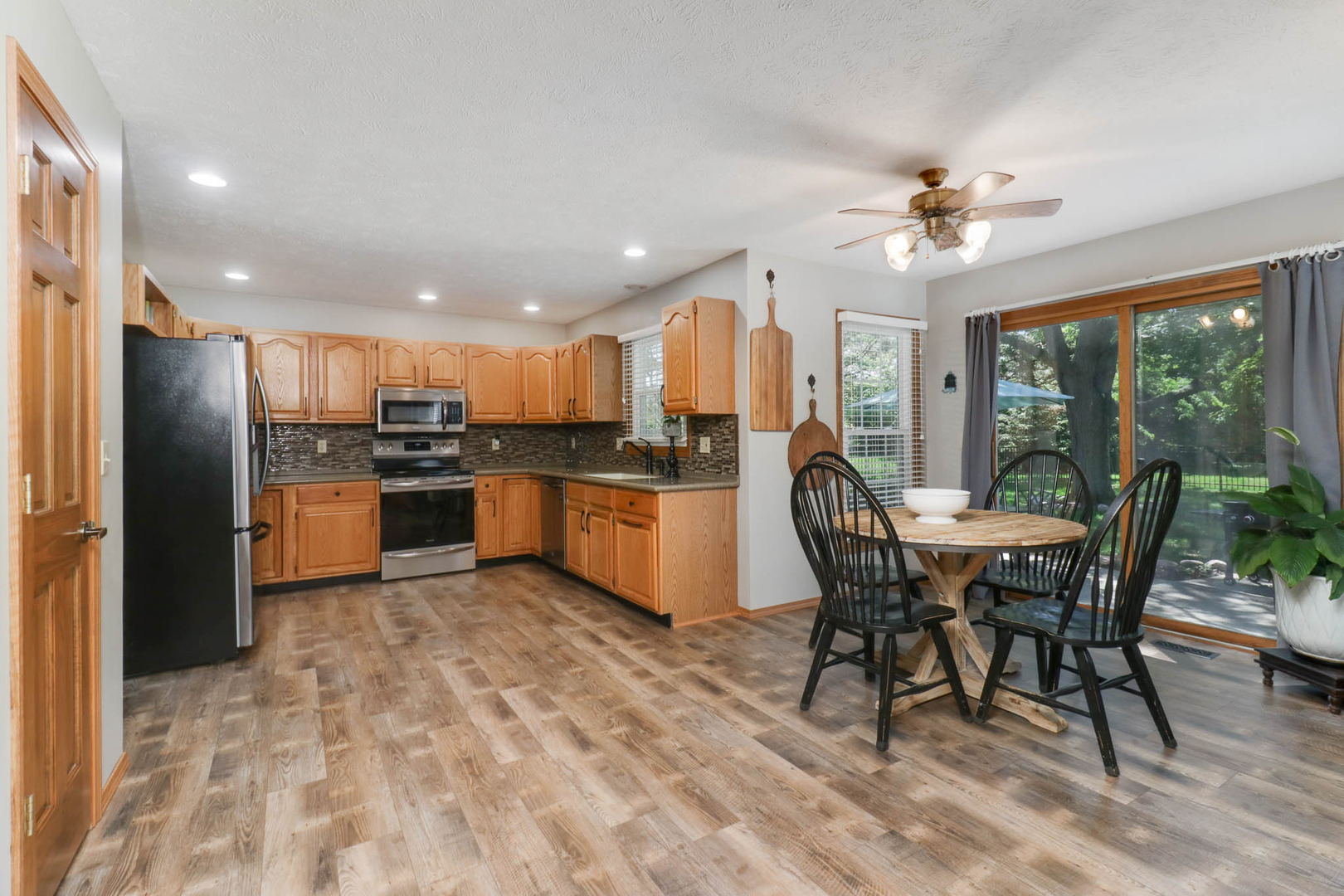 3203 Eagle Crest Road Bloomington, IL 61704 - Photo 8 of 52 a kitchen with stainless steel appliances kitchen island granite countertop a refrigerator a stove a sink a dining table and chairs with wooden floor