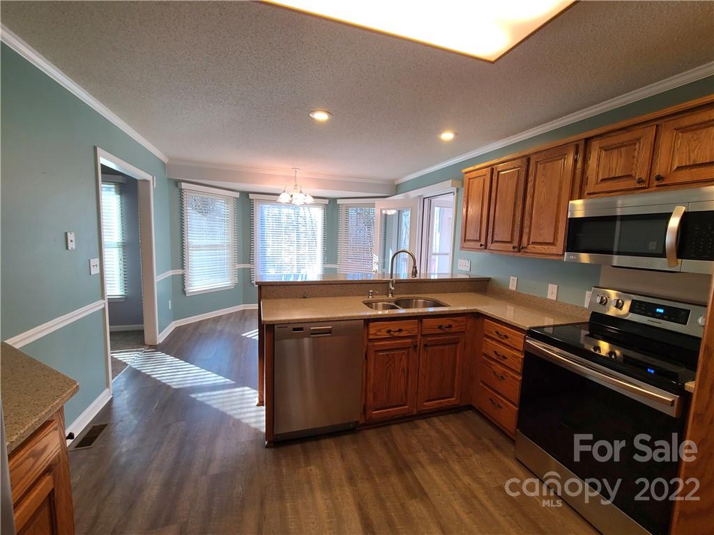 24955 Ridgecrest Road Locust, NC 28097 - Photo 7 of 22 a kitchen with stainless steel appliances granite countertop wooden cabinets a stove a sink and a refrigerator