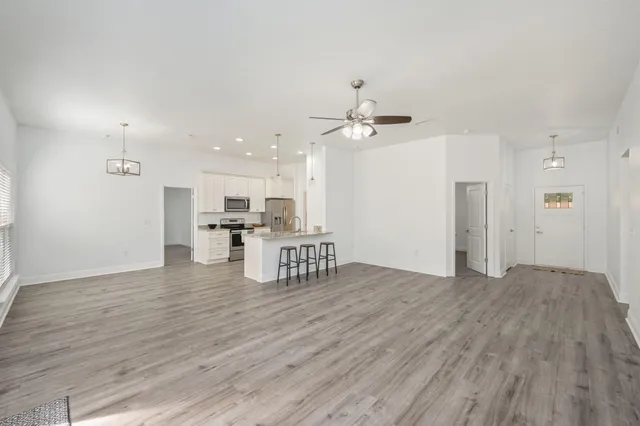 a view of an empty room with kitchen and wooden floor