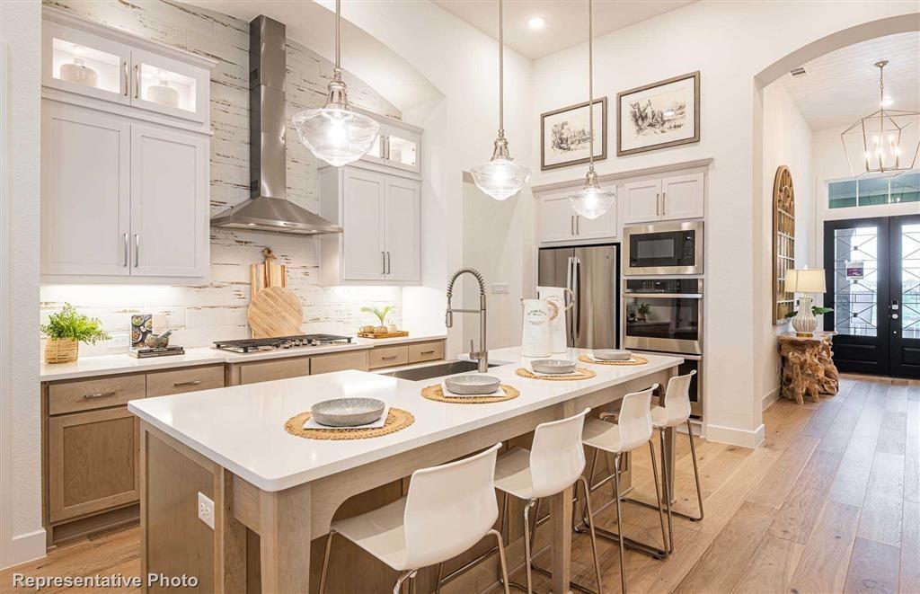 a kitchen with stainless steel appliances granite countertop a table chairs stove and wooden floor