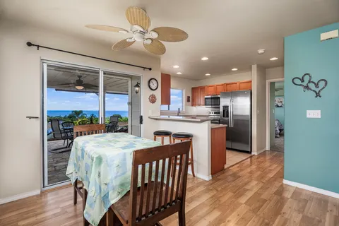 a kitchen with stainless steel appliances kitchen island granite countertop a table chairs and a refrigerator