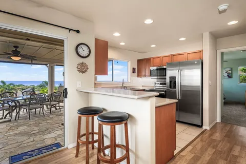 a kitchen with stainless steel appliances granite countertop a stove a refrigerator a kitchen island a dining table and chairs with wooden floor