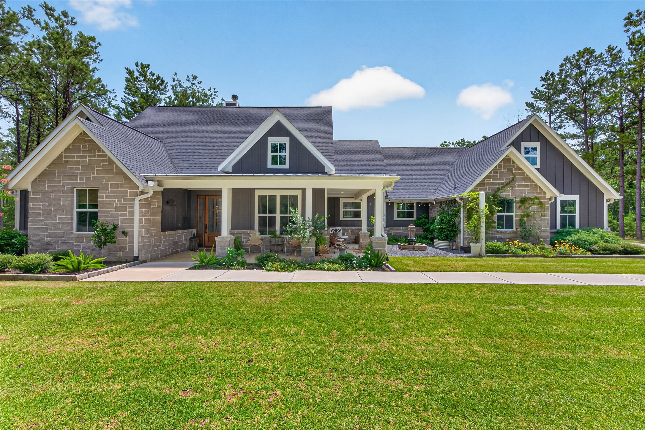 10915 Ruger Road Willis, TX 77378 - Photo 1 of 50 This charming home boasts stunning curb appeal with a beautifully landscaped front yard, inviting porch, and a harmonious blend of stone and siding exterior, all set against a backdrop of lush greenery.