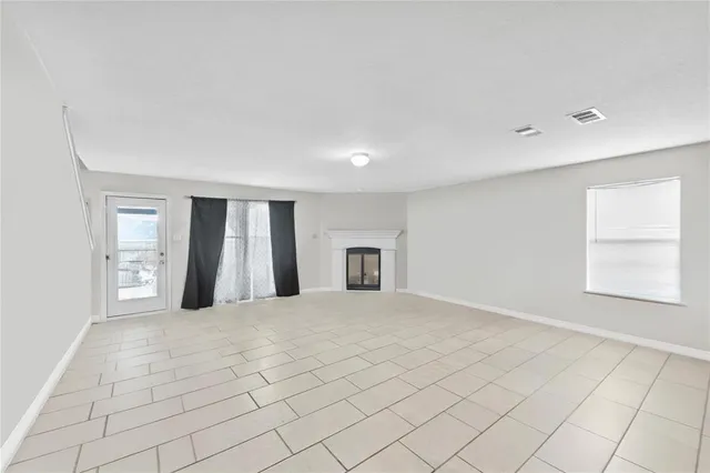 a view of an empty room with window and wooden floor