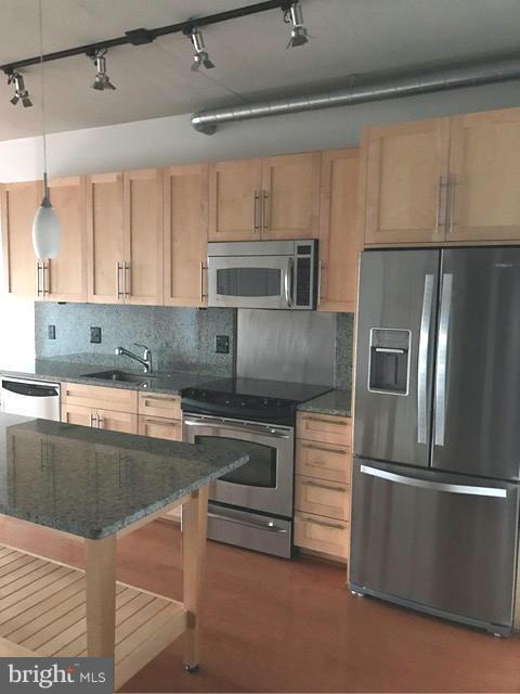 2125 14th Street Northwest, Unit 527 Washington, DC 20009 - Photo 6 of 20 a kitchen with kitchen island a counter top space a sink stainless steel appliances and cabinets