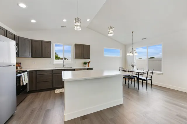 a kitchen with kitchen island granite countertop a sink and refrigerator