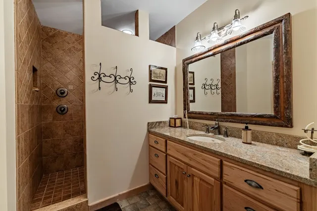a bathroom with a granite countertop sink a mirror and a shower