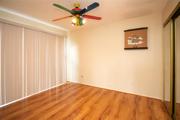 an empty room with a ceiling fan and wooden floor