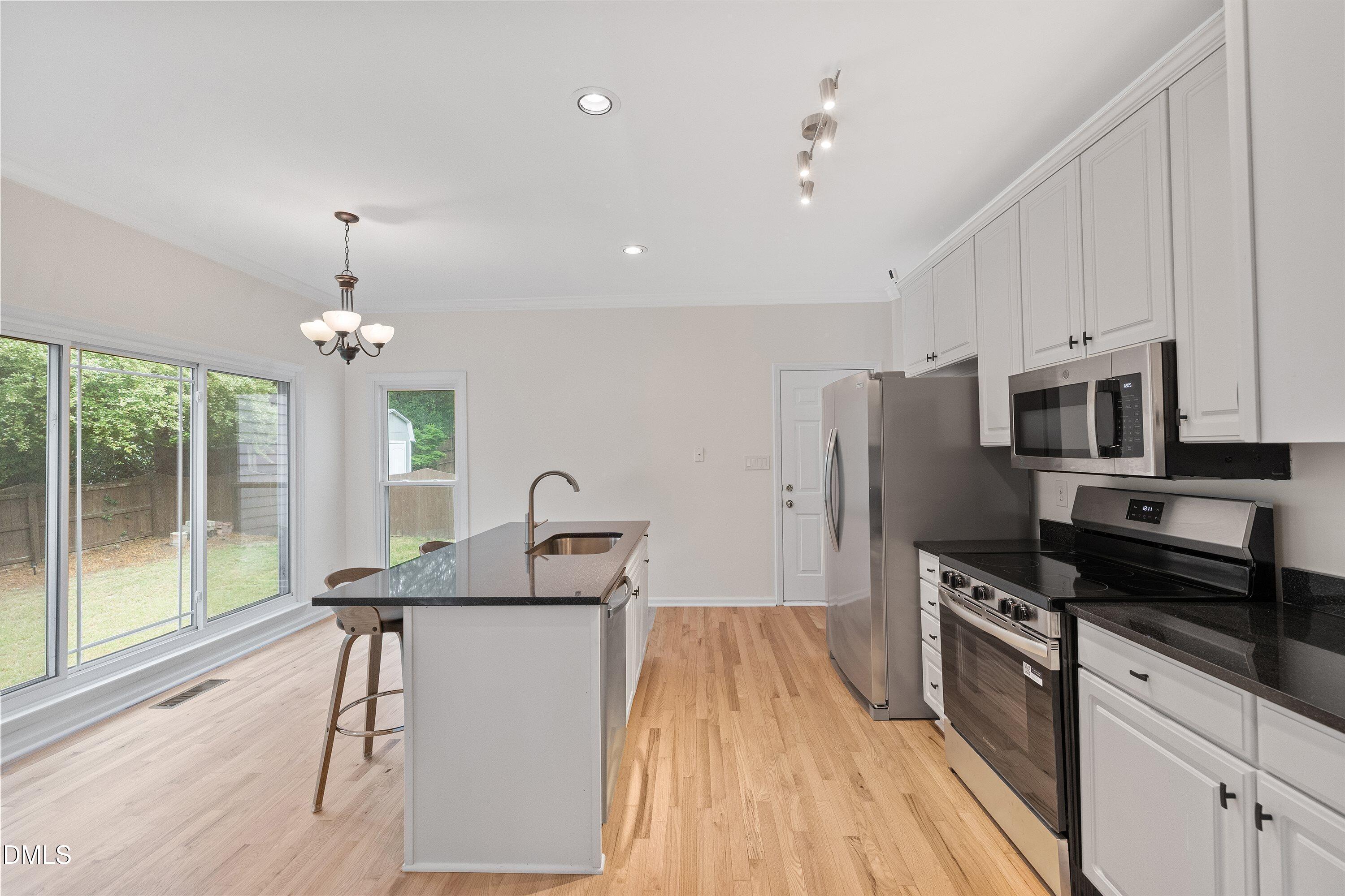 2428 Havershire Drive Raleigh, NC 27613 - Photo 19 of 53 a kitchen with stainless steel appliances kitchen island granite countertop a refrigerator a stove a microwave oven with a dining table and chairs