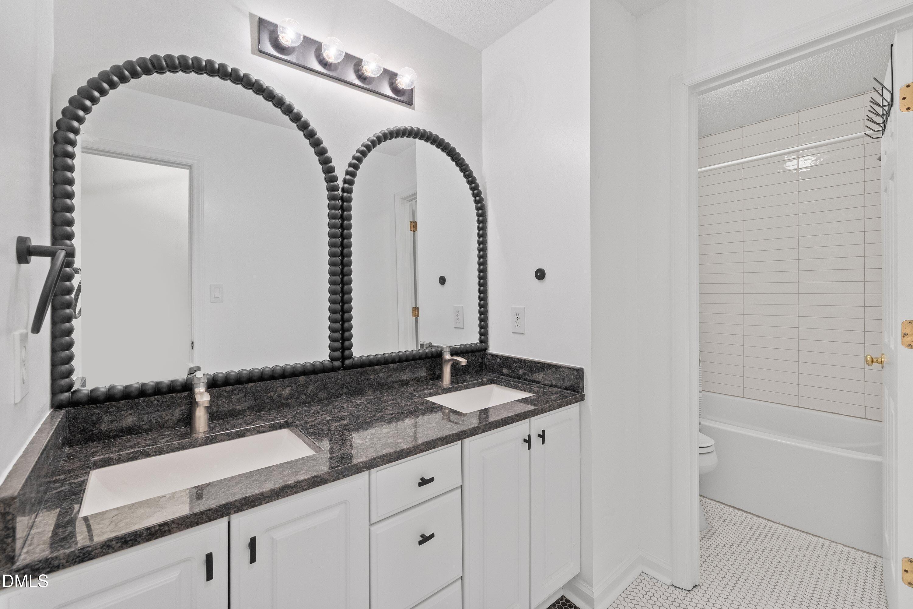 2428 Havershire Drive Raleigh, NC 27613 - Photo 34 of 53 a bathroom with a granite countertop sink a mirror and shower
