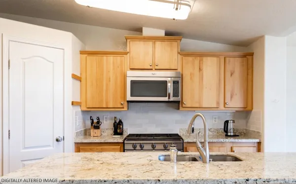 a kitchen with stainless steel appliances granite countertop a stove a sink and a microwave