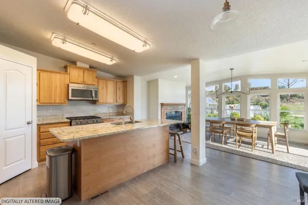 a kitchen with stainless steel appliances a stove top oven a sink a dining table and chairs