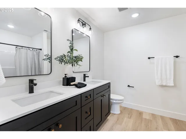 a bathroom with a double vanity sink toilet and mirror