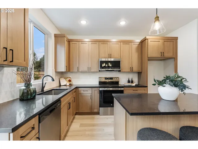 a kitchen with kitchen island granite countertop a sink stainless steel appliances and cabinets