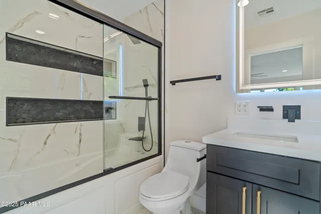 a view of an empty room and kitchen with a ceiling fan
